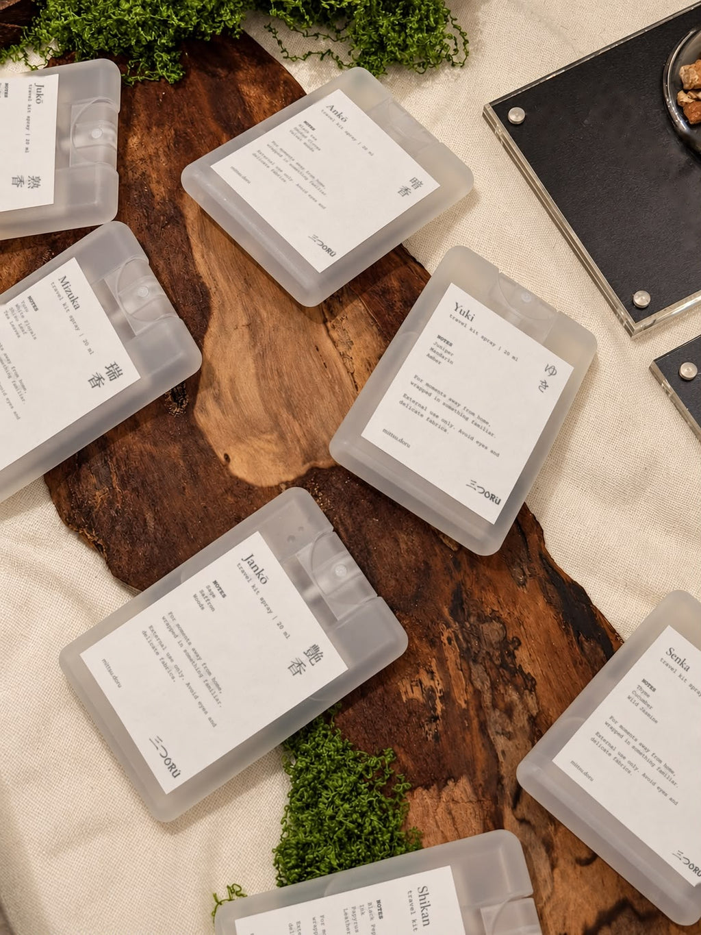 All seven Mittsu Doru Pocket Mists laid out on a wooden board with moss